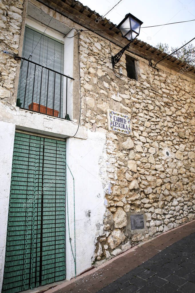 Escola Street and typical facade with street name plate of Benifato village in Alicante, Spain