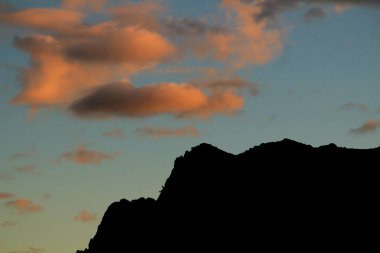 Guadalest, Alicante, İspanya 'da renkli bulutlar ve dağların siluetiyle muhteşem bir gün batımı.