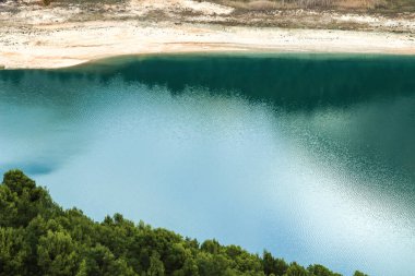 Güneşli bir günde çevresi bitki örtüsü ve dağlarla çevrili Guadalest köyünün renkli bataklığında yansımalar.