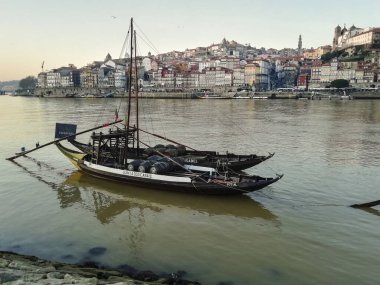 Porto, Portekiz- 7 Mart 2022: Porto şehrinin ve Douro Nehri 'nin kışın günbatımında Rabelos adı verilen teknelerinin manzarası