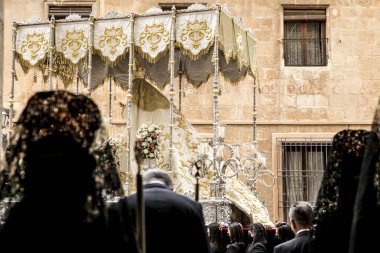 Elche, İspanya - 13 Nisan 2022: Paskalya Geçidi 'nde Santa Maria kilisesinden dışarı çıkan mantilla elbiseleri giyen kadınlar ve hamileler ile Bakire Meryem.