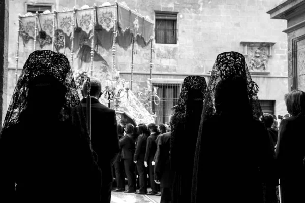 Elche, İspanya - 13 Nisan 2022: Paskalya Geçidi 'nde Santa Maria kilisesinden dışarı çıkan mantilla elbiseleri giyen kadınlar ve hamileler ile Bakire Meryem.