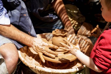 Finestrat, Alicante, Spain- April 23, 2022: Father teaching his son the potter's trade at the Gastronomic and Traditional Market of Finestrat