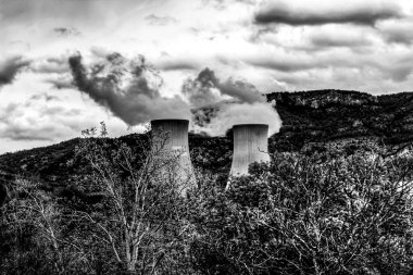 Valencia, İspanya 'daki dağların arasında Cofrentes' teki bacalar tütütüyor.
