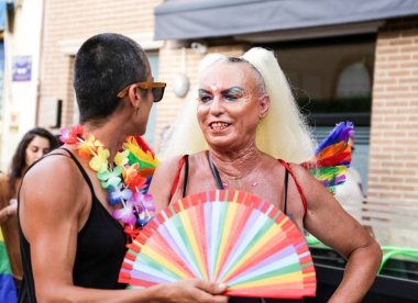 Santa Pola, Alicante, Spain- July 2, 2022: Spanish People attending Gay Pride Parade with rainbow flags, banners and colorful costumes