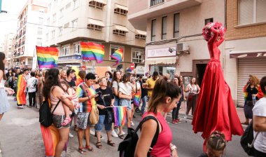 Santa Pola, Alicante, Spain- July 2, 2022: Spanish People attending Gay Pride Parade with rainbow flags, banners and colorful costumes