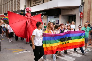 Santa Pola, Alicante, İspanya - 2 Temmuz 2022: İspanya Gay Onur Yürüyüşü 'ne gökkuşağı bayrakları, afişler ve renkli kostümlerle katılıyor