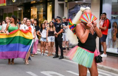 Santa Pola, Alicante, Spain- July 2, 2022: Spanish People attending Gay Pride Parade with rainbow flags, banners and colorful costumes