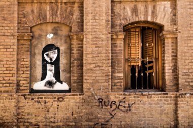Cartagena, Murcia, Spain- July 17, 2022: Broken and damaged window in an old house next to graffiti picture in Spain