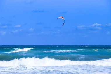 Alicante, Spainl- 18 Eylül 2022: Arenales del Sol plajında mavi gökyüzü ve dalgalı Akdeniz altında sörfçü