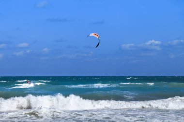 Alicante, Spainl- 18 Eylül 2022: Arenales del Sol plajında mavi gökyüzü ve dalgalı Akdeniz altında sörfçü