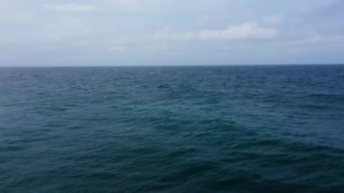 Koyu mavi deniz ve bulutlu gökyüzü.