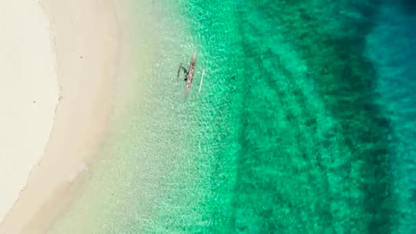 Лагуна с чистой морской водой и белым песчаным пляжем, вид сверху. Человек с лодкой в голубой лагуне. — стоковое видео