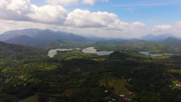 Tropisch landschap: Landbouwgrond met aanplant tegen een achtergrond van bergen en blauwe lucht.. — Stockvideo