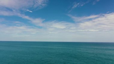 Dalgalı mavi okyanus ve bulutlu mavi gökyüzü.
