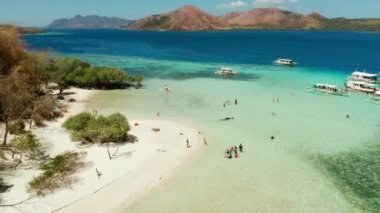 Hava deniz manzaralı turistler tropikal plajların keyfini çıkarırlar. Kum plajı döngüsü olan tropik bir ada, palmiye ağaçları. Filipinler, Palawan. Mavi lagün ve mercan resifli tropik bir manzara.