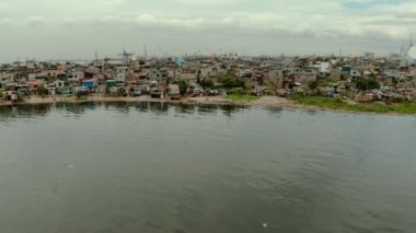 Limanın yakınındaki gecekondu mahallelerinde yerel halk kulübeleri ve nehir kıyısı yukarıdan gelen çöplerle dolup taşıyor. Manila, Filipinler.