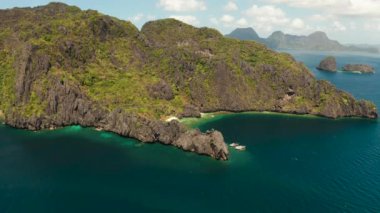 Kumsalı ve kayalıklarla çevrili berrak mavi suyu olan tropik hava aracı peyzajı. El nido, Filipinler, Palawan. Tropikal kayalık adaları, okyanus mavisi suları olan deniz burnu. Yaz ve seyahat