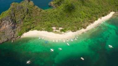 Palmiye ağaçları, mavi göl ve masmavi berrak suyla adanın tropikal plajı. Sahildeki tropik adada turist botları. El Nido, Palawan Filipinleri 'ndeki helikopter adası. Tropikal manzara