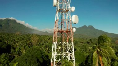 Telekomünikasyon kulesi, dağlara ve yağmur ormanlarına karşı iletişim anteni, hava manzarası. Metal bir kulede tekrarlayıcılar. Camiguin, Filipinler