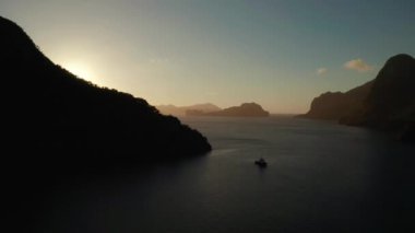 Sabahları El Nido 'da dağları ve kayalık adaları olan hava aracı deniz manzarası. Denizin üzerinde gün batımı. Tropikal körfez gün batımında. Gün batımı gökyüzü ve körfez kayaları. Kayaların arasında rüya gibi gün batımı