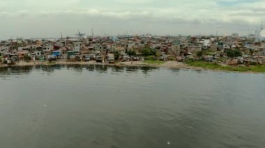 Limanın yakınındaki gecekondu mahallelerinde yerel halk kulübeleri ve nehir kıyısı yukarıdan gelen çöplerle dolup taşıyor. Manila, Filipinler.