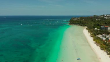 Mavi deniz kıyısında turistlerin ve otellerin olduğu tropik beyaz plaj, hava manzaralı. Yaz ve seyahat tatil konsepti.