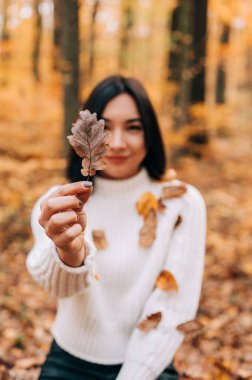 Elinde kuru yaprak tutan bir kızın eli. Mevsimsel sonbahar arka planında yalıtılmış yaprak.