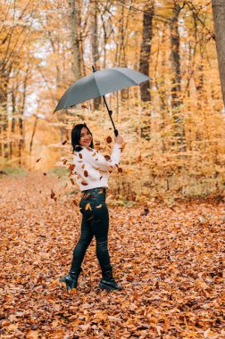 Ormanda yürüyen, şemsiyeyle oynayan ve sonbahar mevsiminde ayrılan tatlı genç kız..