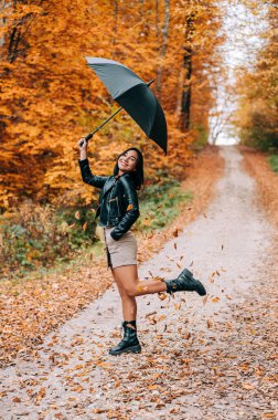 Ormanda yürüyen, şemsiyeyle oynayan ve sonbahar mevsiminde ayrılan tatlı genç kız..