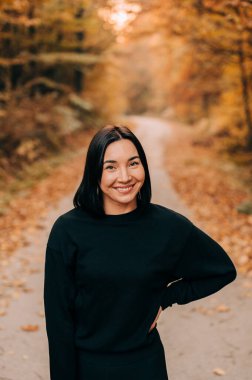 Renkli sonbahar sezonunda ormanda genç bir kadının portresi. Ormanda poz veren mutlu kız..