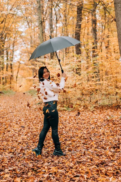 Ormanda yürüyen, şemsiyeyle oynayan ve sonbahar mevsiminde ayrılan tatlı genç kız..