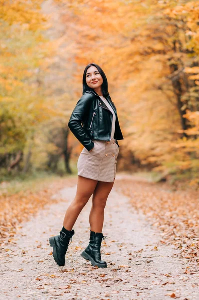Ormanda modern kıyafetlerle poz veren güzel Avrupalı bir kızın tam boy portresi. Sonbahar mevsiminde orman.
