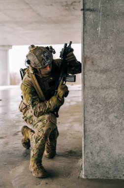 Multicam üniformalı özel kuvvetler operatörü ve saldırı tüfeği HK 416 terk edilmiş binada CQB savaş eğitimi alırken. Kentsel çevrede çakal kahverengi ve MC dişlisi.