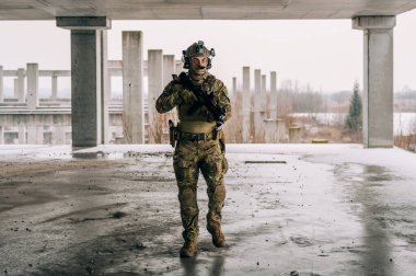 Multicam üniformalı özel kuvvetler operatörü ve saldırı tüfeği HK 416 terk edilmiş binada CQB savaş eğitimi alırken. Kentsel çevrede çakal kahverengi ve MC dişlisi.