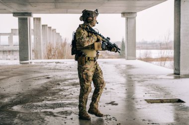 Multicam üniformalı özel kuvvetler operatörü ve saldırı tüfeği HK 416 terk edilmiş binada CQB savaş eğitimi alırken. Kentsel çevrede çakal kahverengi ve MC dişlisi.