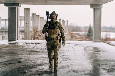 Multicam üniformalı özel kuvvetler operatörü ve saldırı tüfeği HK 416 terk edilmiş binada CQB savaş eğitimi alırken. Kentsel çevrede çakal kahverengi ve MC dişlisi.