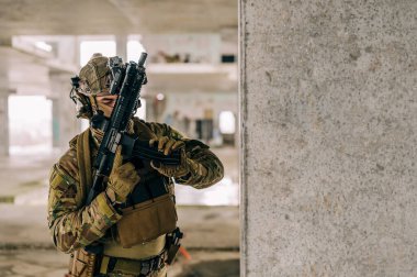 Multicam üniformalı özel kuvvetler operatörü ve saldırı tüfeği HK 416 terk edilmiş binada CQB savaş eğitimi alırken. Kentsel çevrede çakal kahverengi ve MC dişlisi.