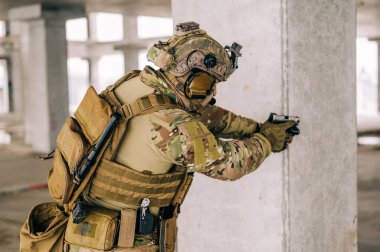 Terk edilmiş binada CQB savaş eğitimi alırken Multicam üniforması ve tabancası xDM 9mm ile özel kuvvetler operatörü. Kentsel çevrede silahlı çakal kahverengi ve MC teçhizatı.