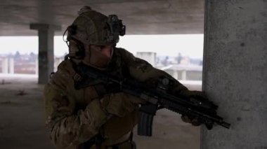 Multicam üniformalı özel kuvvetler operatörü ve saldırı tüfeği HK 416 terk edilmiş binada CQB savaş eğitimi alırken. Kentsel çevrede çakal kahverengi ve MC dişlisi.