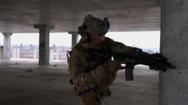 Multicam üniformalı özel kuvvetler operatörü ve saldırı tüfeği HK 416 terk edilmiş binada CQB savaş eğitimi alırken. Kentsel çevrede çakal kahverengi ve MC dişlisi.