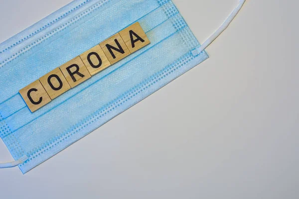 The word corona on wood with face mask on white background