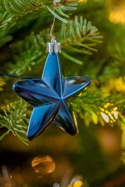 Noel ağacının süsü olarak mavi Noel yıldızını kapat, seçici bir odak noktası.