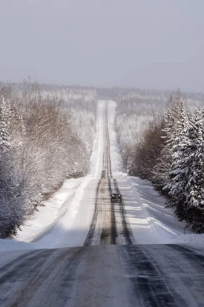 Quebec 216 yolu, Chaudiere-Appalaches bölgesinde, kışın, kısmi karlı yolun etrafındaki kar ormanının geniş panoramik manzarasıyla. 