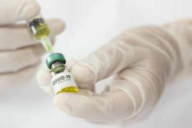 Doktor, hemşire, bilim adamı eli COVID-19 Coronavirus aşısı içeren şırınga ve şişe eldiveni giyer. COVID-19 Coronavirus, Sağlık ve Tıp Konseptine karşı aşı..