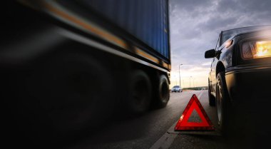 Kırmızı acil durum dur işareti (kırmızı üçgen uyarı işareti) ve güzel gün batımı gökyüzü, seçici odak ve uzun deklanşör hızı ile köprü üzerinde kırık siyah SUV araba.