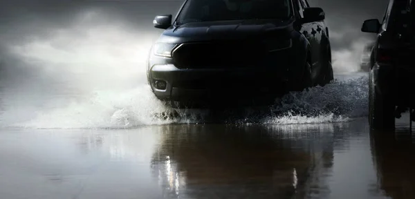 車は車輪からの水噴霧とハード雨の後に洪水の水を介して実行されます — ストック写真