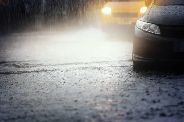 激しい雨が夜に降った後 ヘッドライトと黒の近代的な車のブリュリー運動は洪水の水を通って実行されます — ストック写真