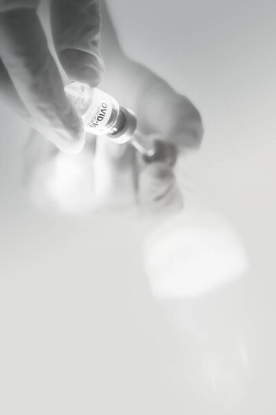 Врач, медсестра, ученый рука носит медицинскую перчатку со шприцем и флакон с коронавирусом COVID-19 для инъекций. Вакцина против коронавируса COVID-19, здравоохранения и медицинской концепции.