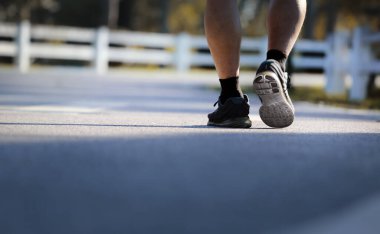Yaşlı bir adamın parkta yürümesine düşük açılı bakış açısı. Sağlıklı bir kavram..